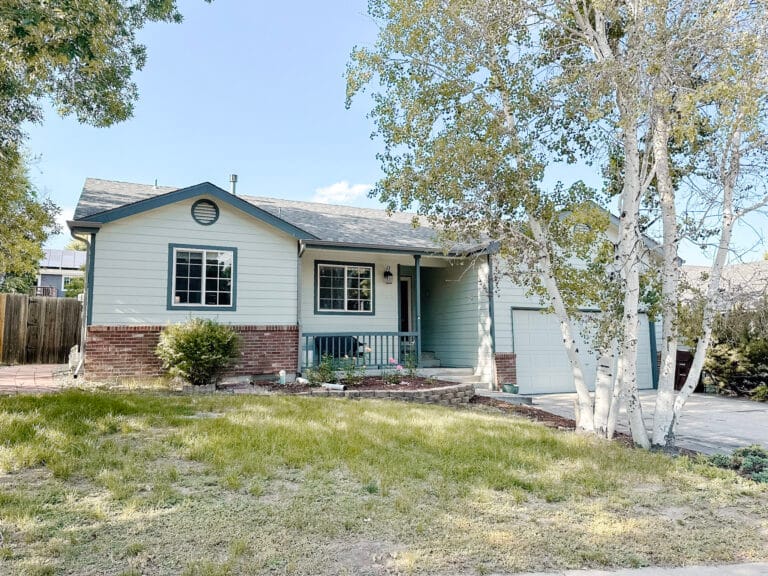 Front lawn with patchy, dying grass with a mint green house.