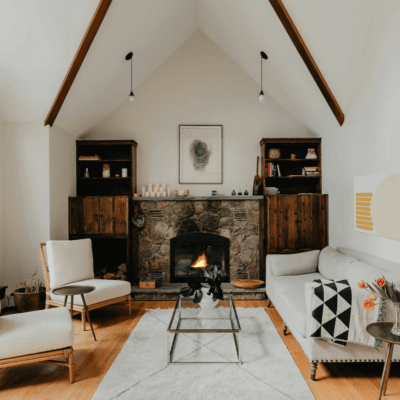 white living room with stone fireplace, tall walls, and white furniture