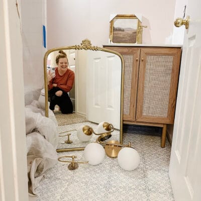small pink bathroom during a renovation with gold and dark wood fixtures laying on the ground