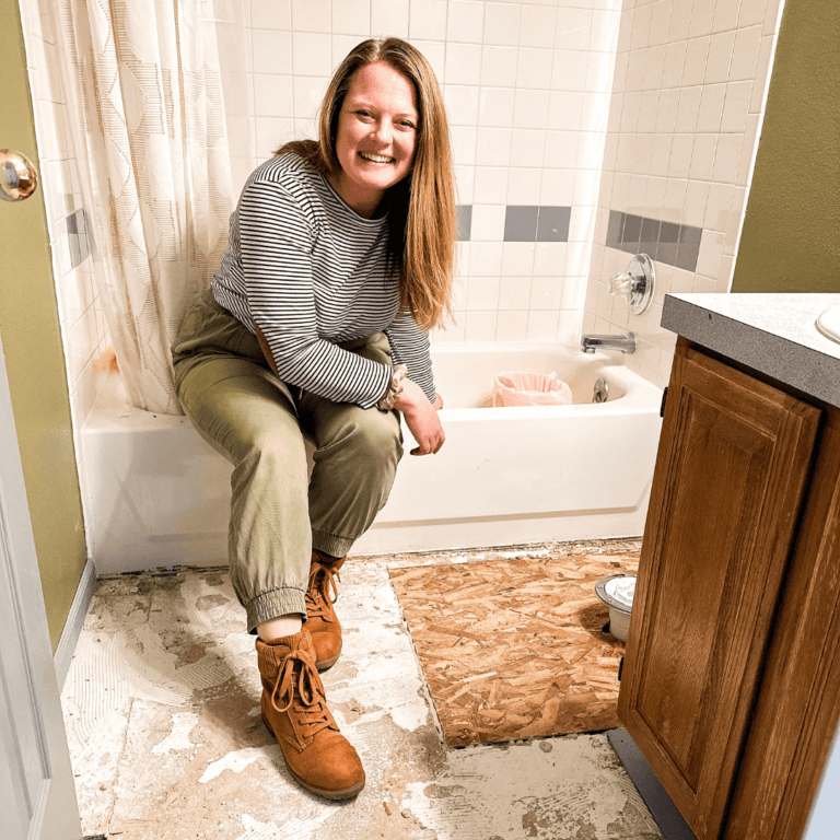 woman sitting on edge of tub in a bathroom renovation with a repaired subfloor