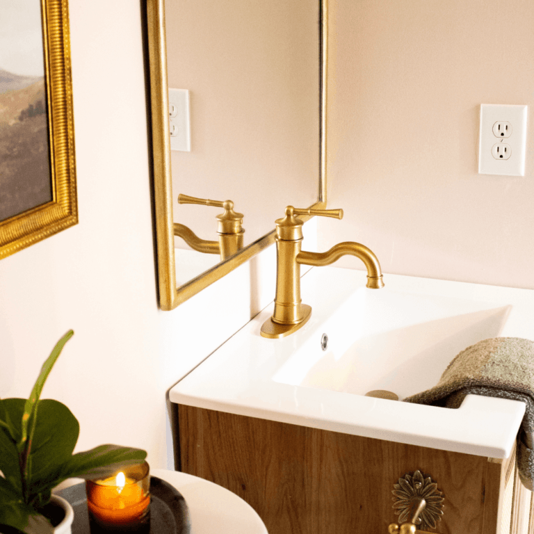 pink bathroom with gold faucet and gold mirror