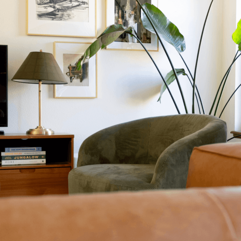 Green barrel chair in a living room with gallery wall and leather couch
