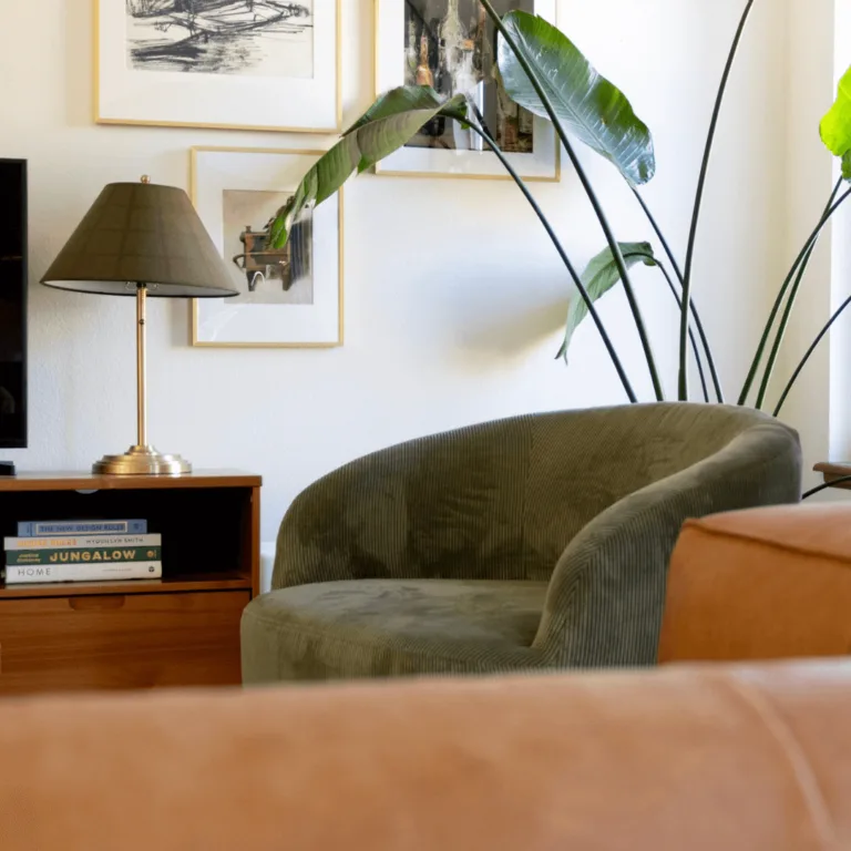 Green barrel chair in a living room with gallery wall and leather couch