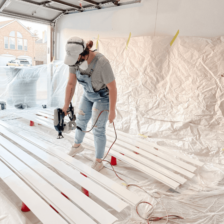 woman painting shiplap with a paint sprayer