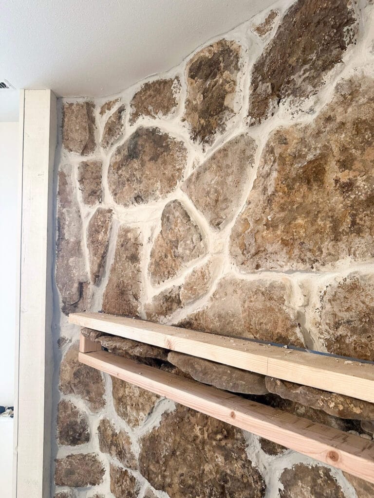 Top half of a tan stone fireplace with white mortar in between the stones