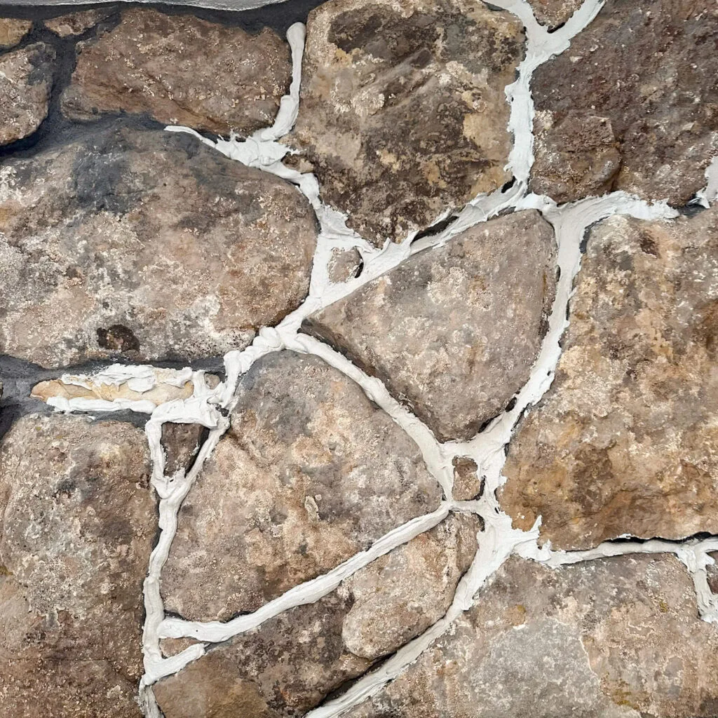 white mortar after being piped onto a tan stone fireplace