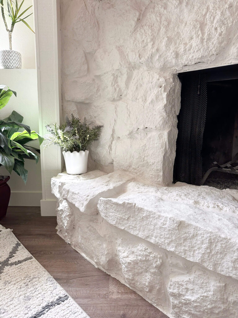 White painted stone fireplace hearth with lavender in a white pot on the hearth