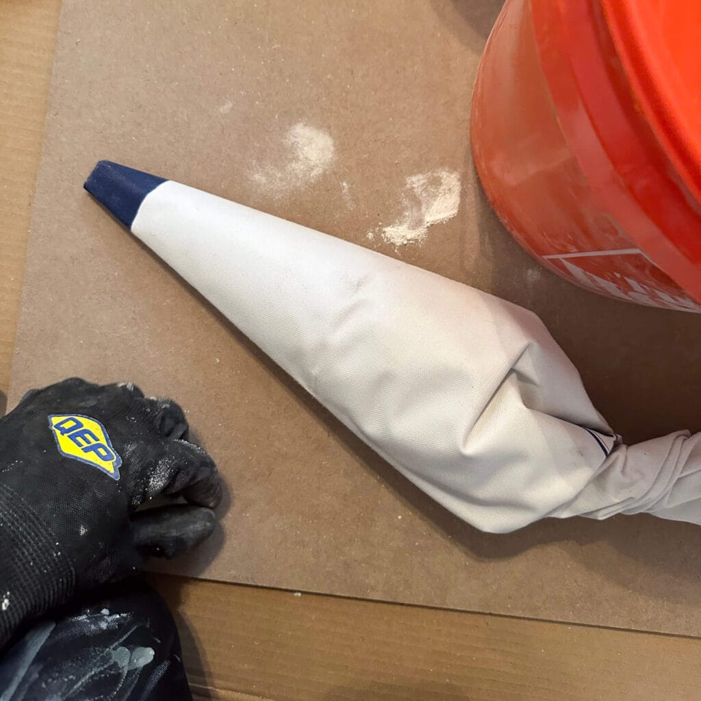 big white piping bag filled with mortar laying down on cardboard