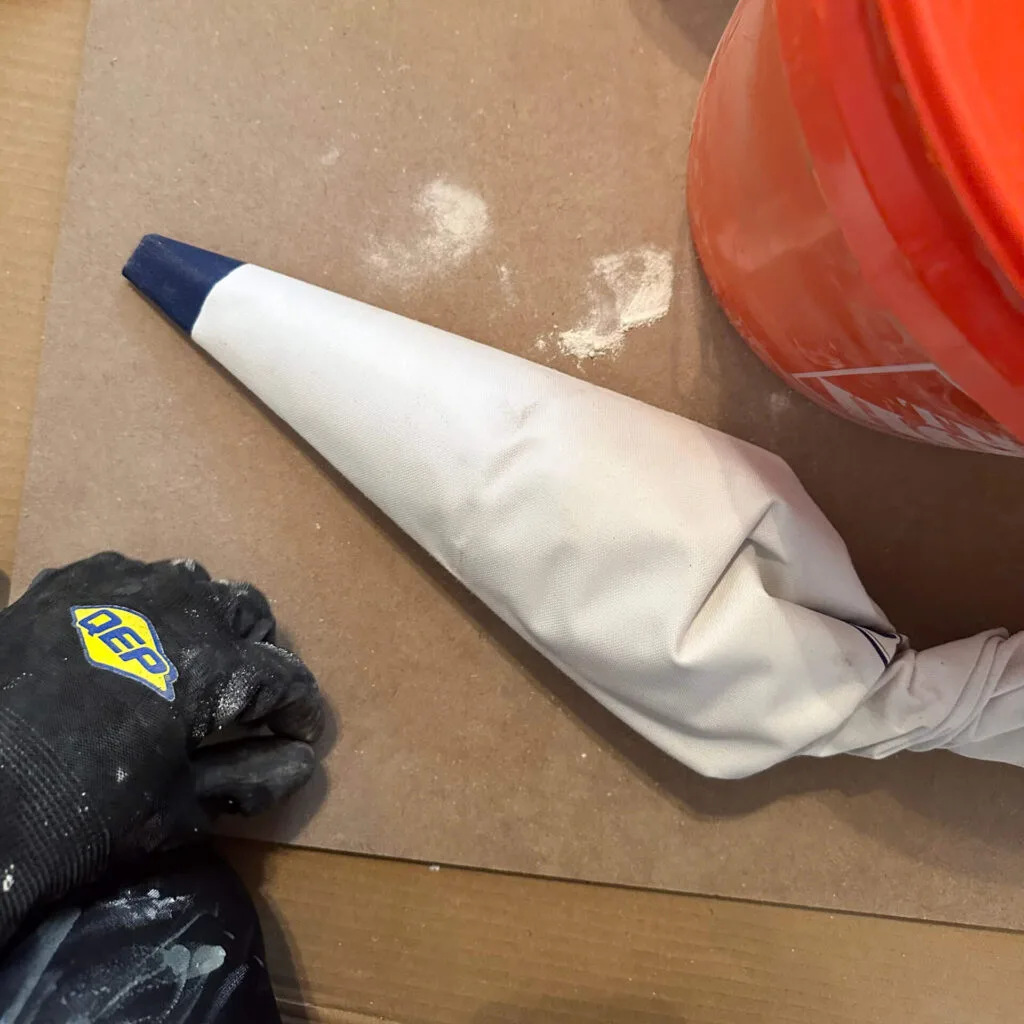 big white piping bag filled with mortar laying down on cardboard