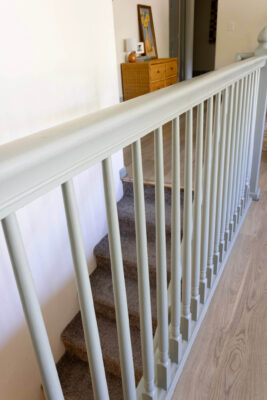 Close-up view of fully painted green stair railing highlighting uniform coverage and clean lines