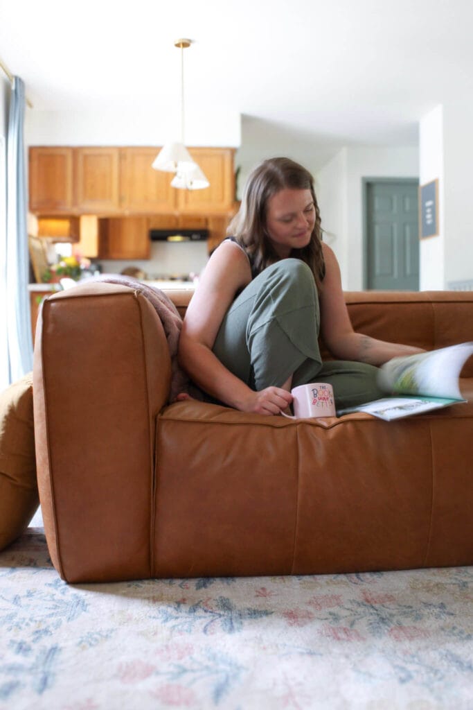 white woman sitting on cognac leather couch reading